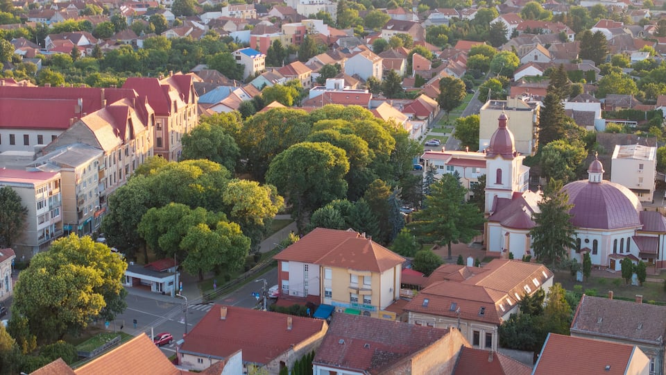 An aerial view of a densely populated urban area with a mix of residential buildings and a prominent church with a red dome.