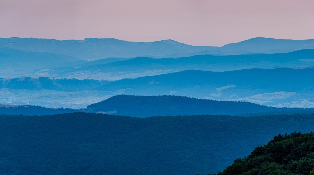 Blue Morning. The mountain ridges of Covasna County, Romania, rise in layered tiers toward the horizon. In the bottom left, a peaceful village lies nestled in the embrace of dawn's first light.