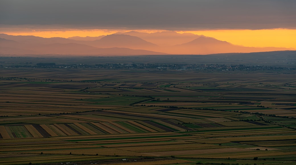 View of the sunset over the agricultural fields and distant mountains in Mereni, Covasna County, Romania.