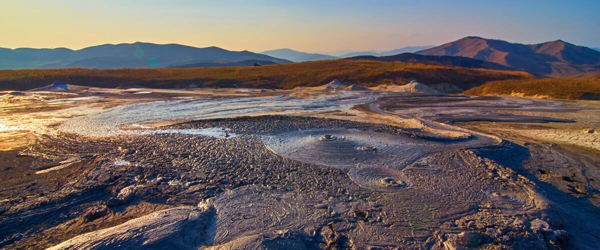 A vast, rugged landscape with rolling hills and a distant mountain range.