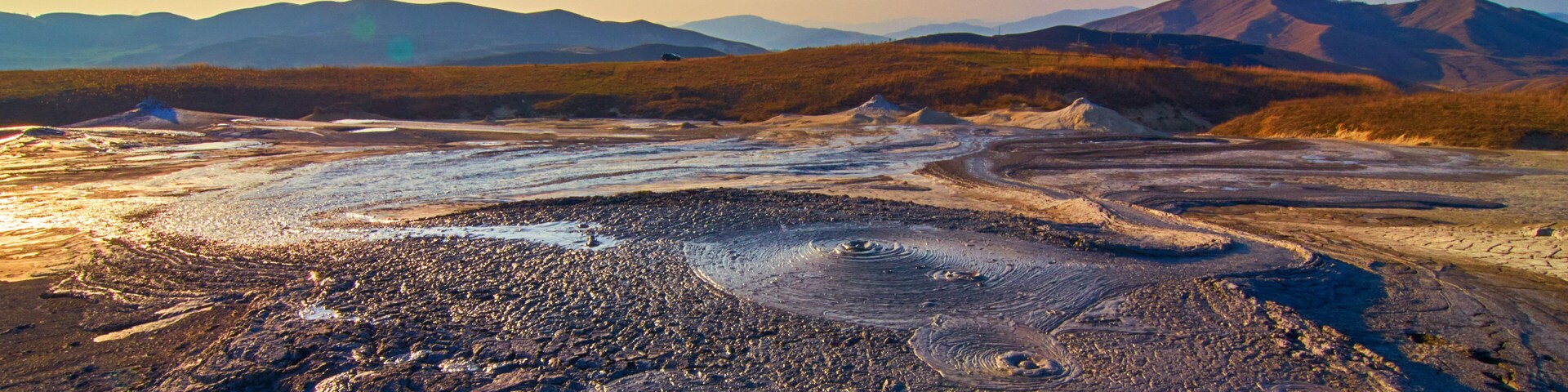 A vast, rugged landscape with rolling hills and a distant mountain range.