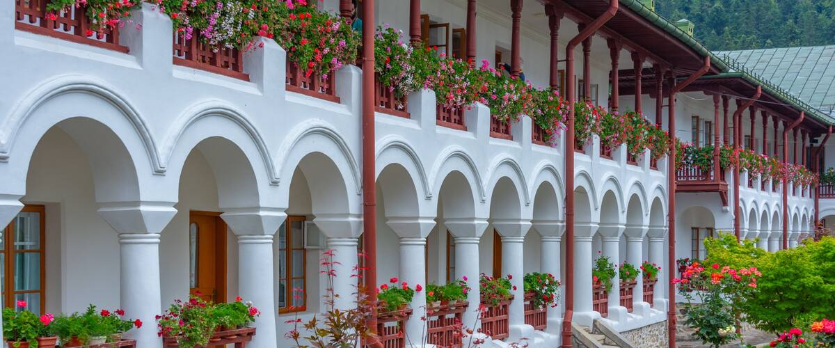A white building with red balconies and flower boxes.