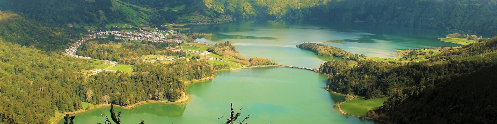 I took this on March 22nd in the Azores Islands, Portugal! It features Lagoa das Sete Cidades (Lagoon of the Seven Cities). This is a twin lake situated in the crater of a dormant volcano. It's one of the Azores' most beautiful and iconic spots! Before the construction of the bridge it was originally one lake. Now it is the "Green Lake" and "Blue Lake". And in the distance you can see the Atlantic Ocean! I actually visited it twice :). On the 2nd day it was much more foggy and cloudy but still very nice!! On both days there was a real feeling of serenity :). I also saw a couple of other lakes similar to this, too. A truly magical green island!!