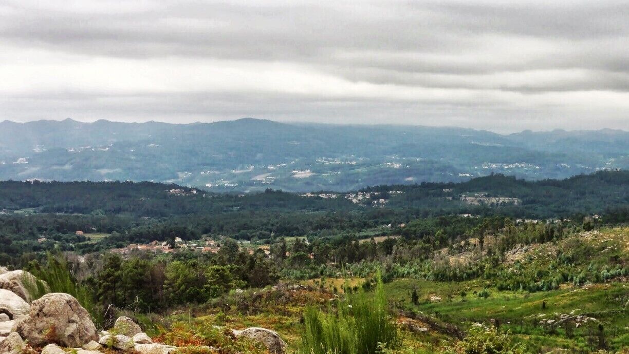 A mountainous landscape with scattered houses and dense forests.