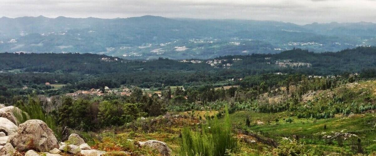 A mountainous landscape with scattered houses and dense forests.