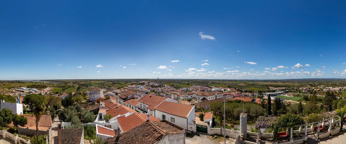 A town with red-tiled roofs, white buildings, and a clear blue sky.