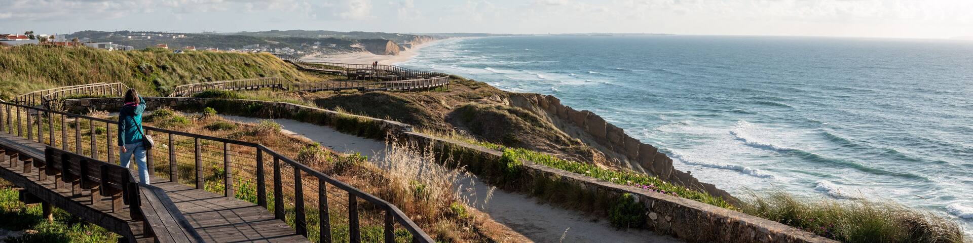 A young woman walking on a boardwalk at the Portuguese coast near Foz do Arelho
