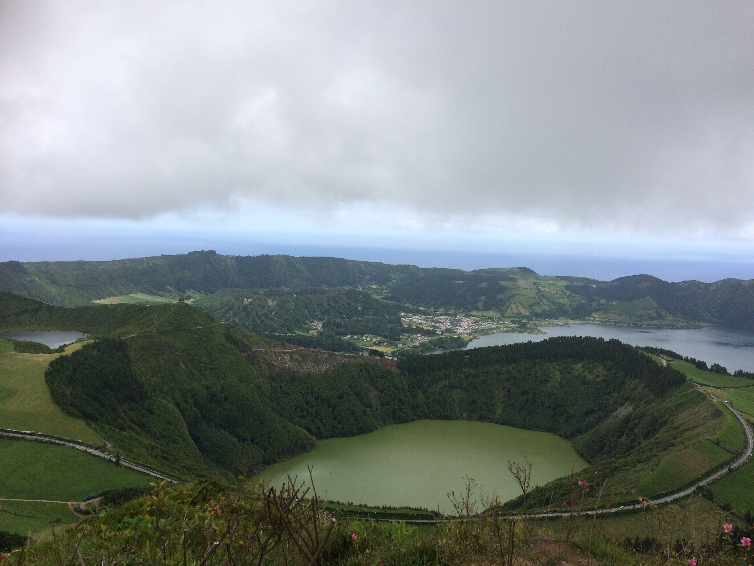 A green valley with a lake surrounded by hills and a small town.
