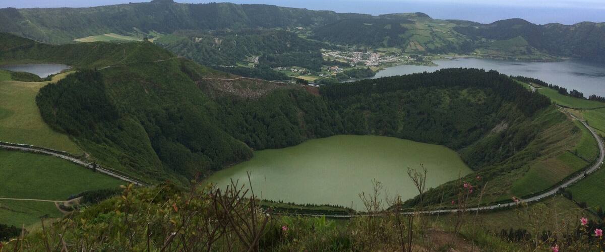 A green valley with a lake surrounded by hills and a small town.