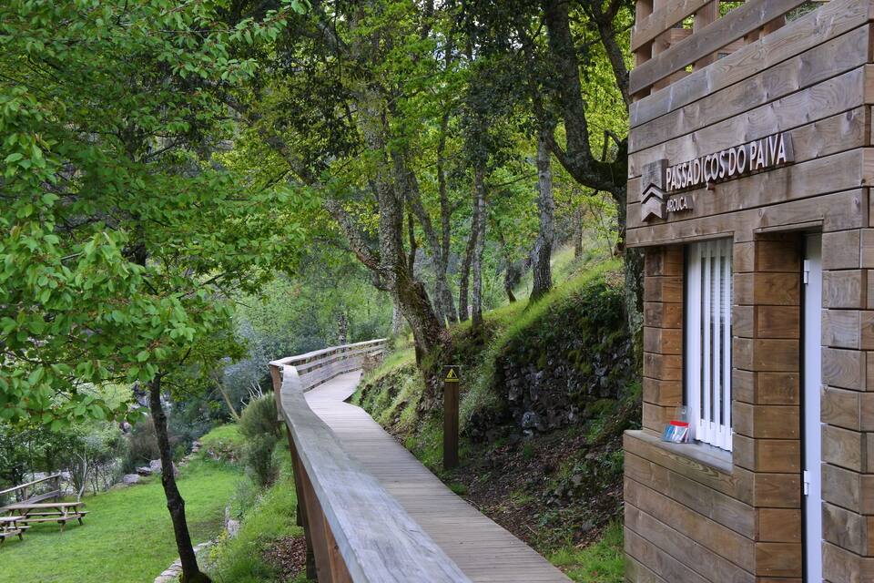 Un paseo marítimo de madera que atraviesa una zona boscosa, con un letrero que dice "PASSADICOS DO PAIVA".