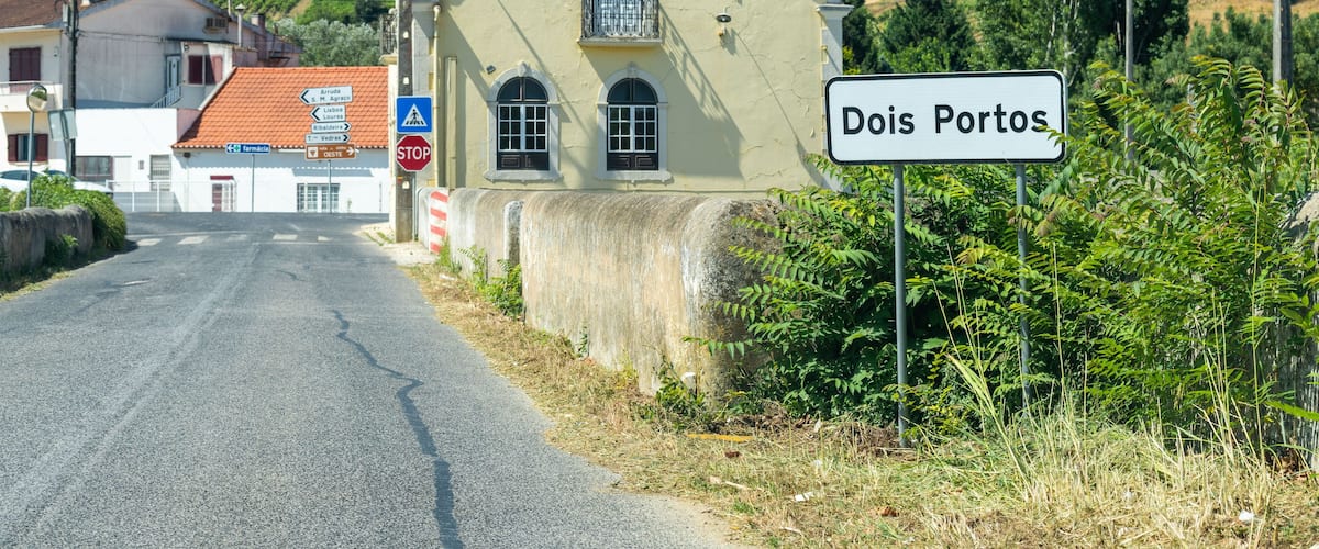 Una carretera rural que conduce a un edificio con un letrero que dice 'Dois Portos'.
