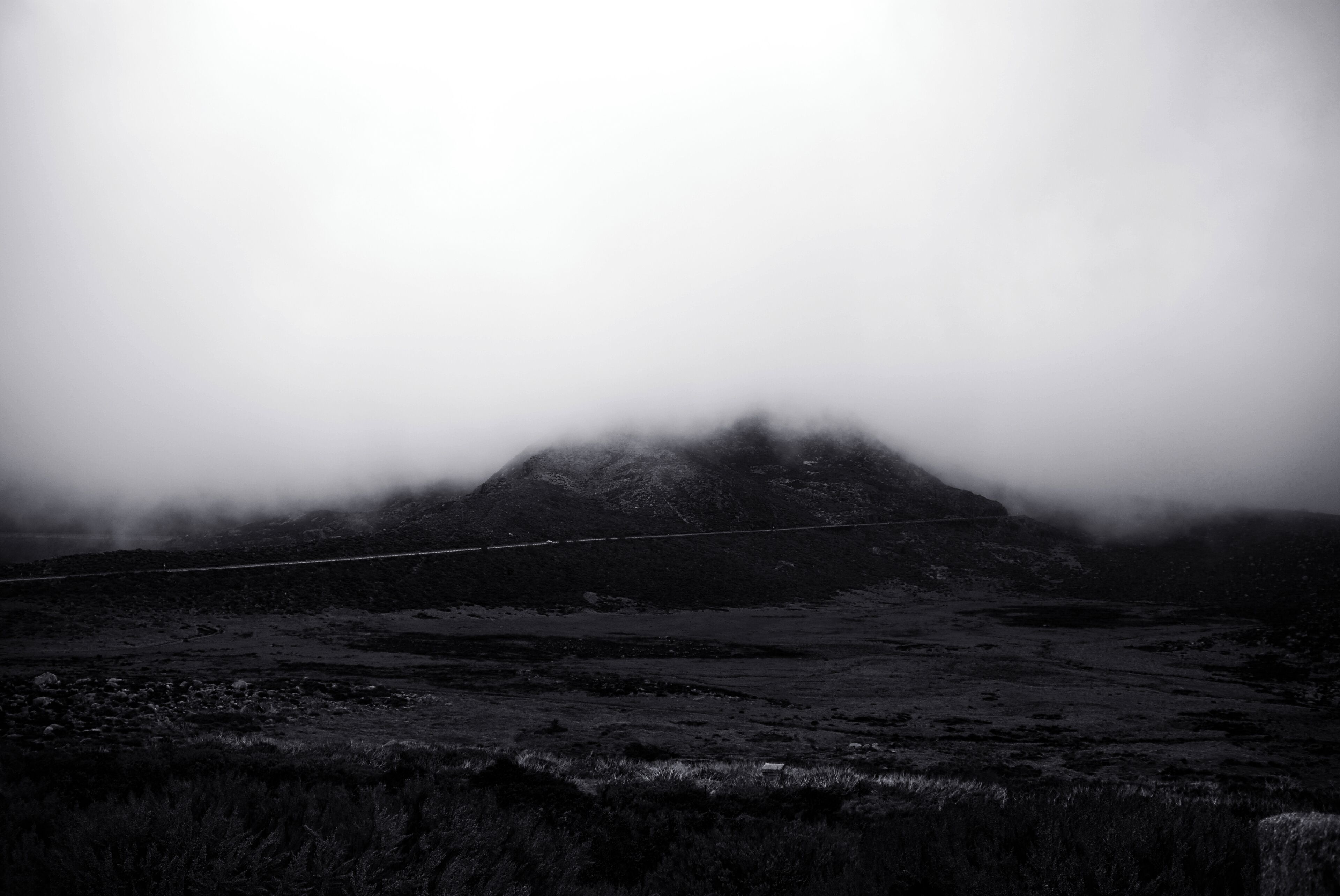 A fog-covered mountain with a road in the foreground.
