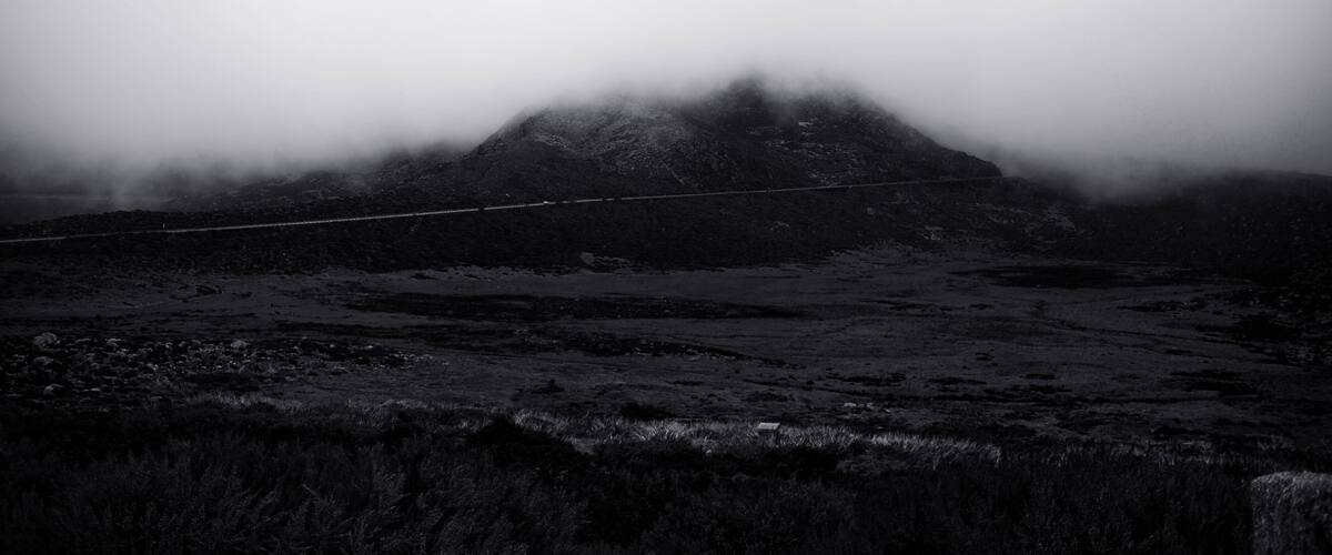 A fog-covered mountain with a road in the foreground.