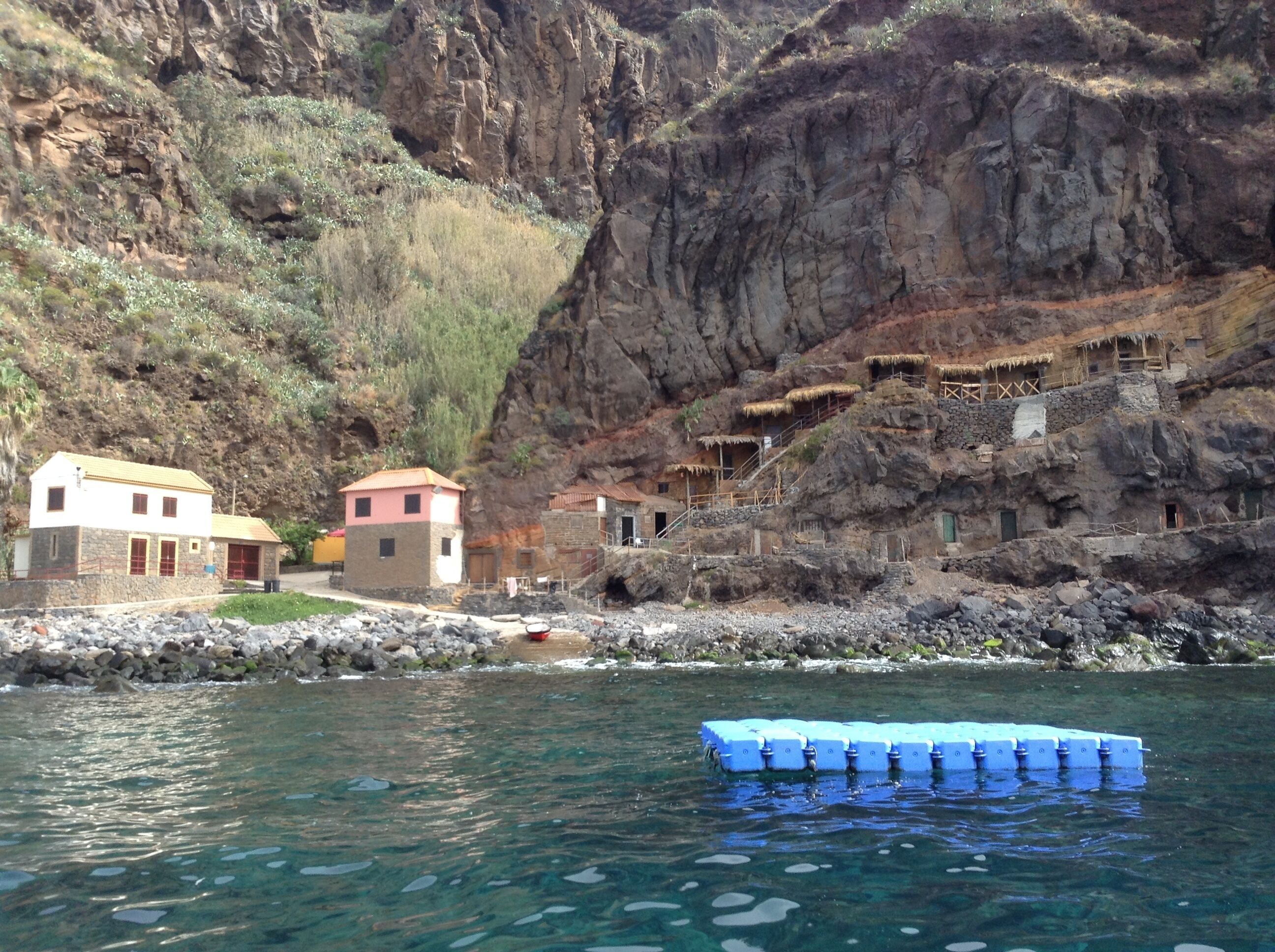 A rocky cliff with traditional stone houses and a clear river.
