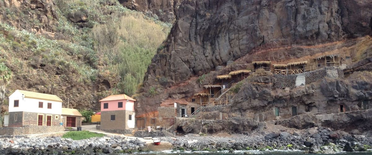 A rocky cliff with traditional stone houses and a clear river.