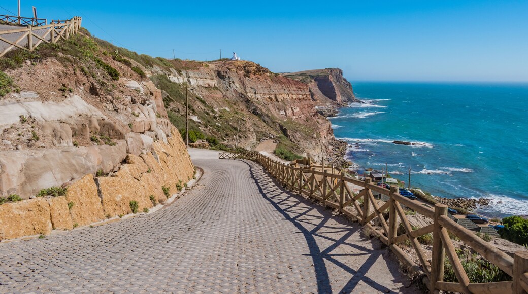 Sidewalk on cliffs with wooden fence and turquoise sea on the horizon at Assenta beach, Ericeira - Mafra PORTUGAL