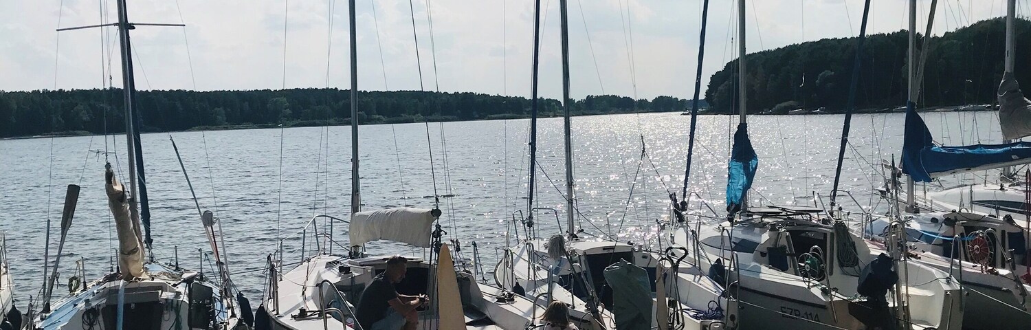 Sailboats docked on a sandy beach with a forested island in the background.
