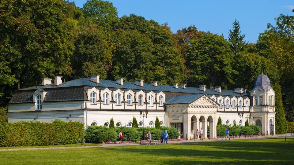 A historic building with a dome, surrounded by lush greenery and a well-maintained lawn.