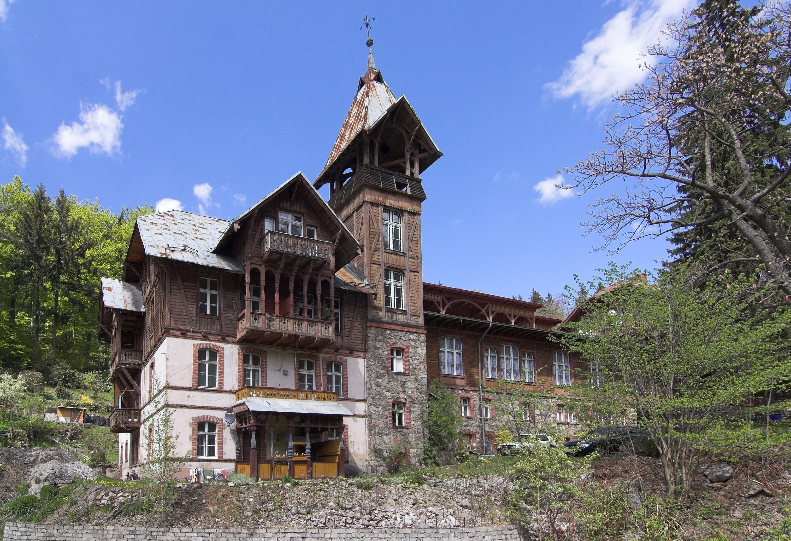 A large, rustic wooden building with a steeply pitched roof and a prominent tower.