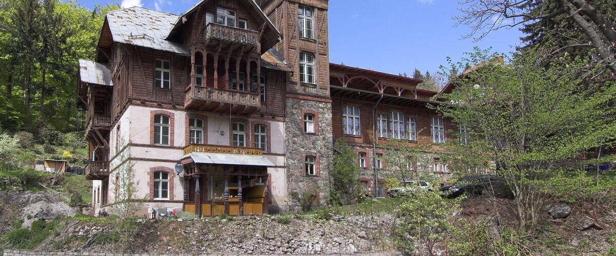A large, rustic wooden building with a steeply pitched roof and a prominent tower.