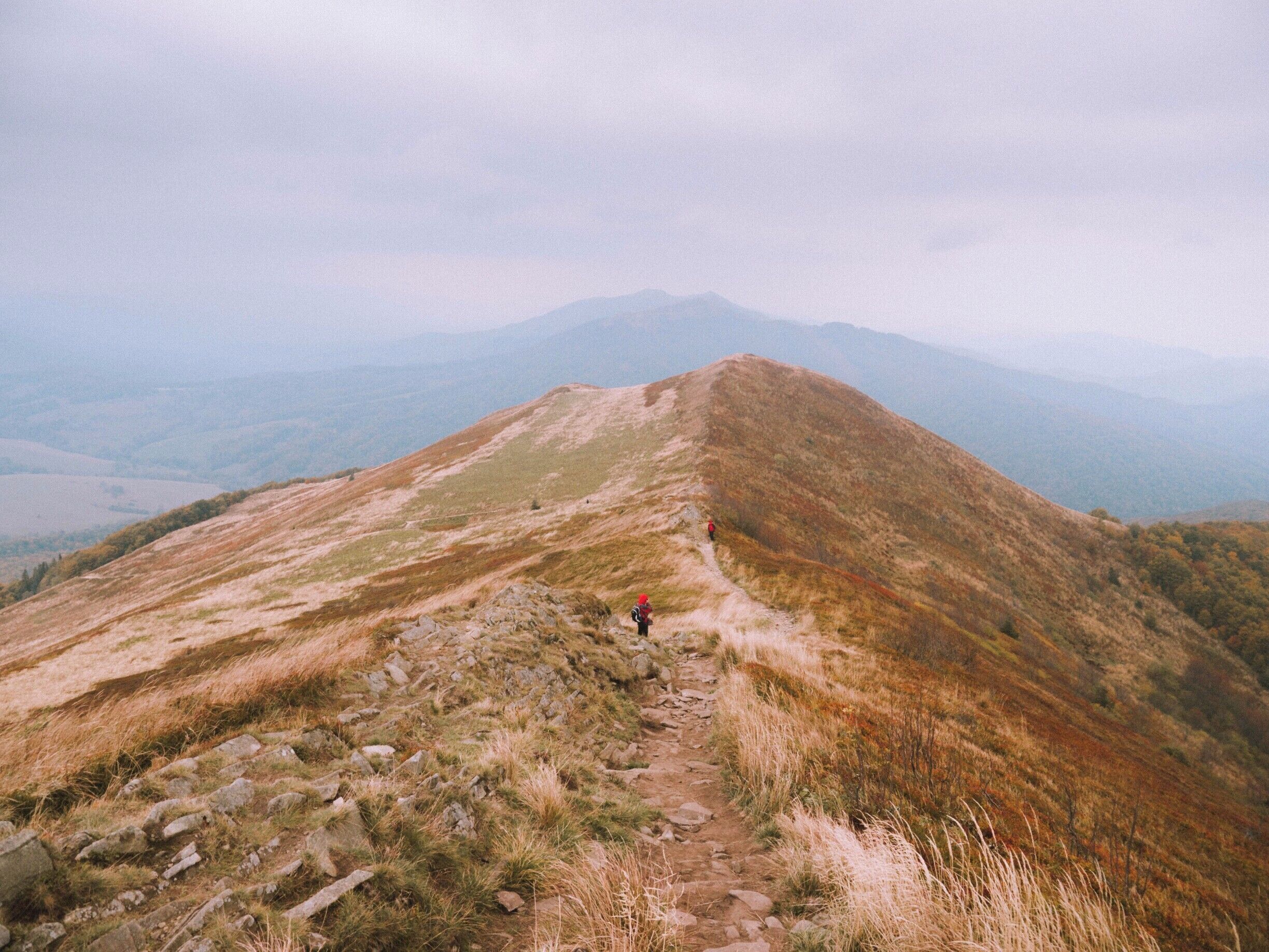 A mountain trail with rocky terrain and a hiker in the distance.