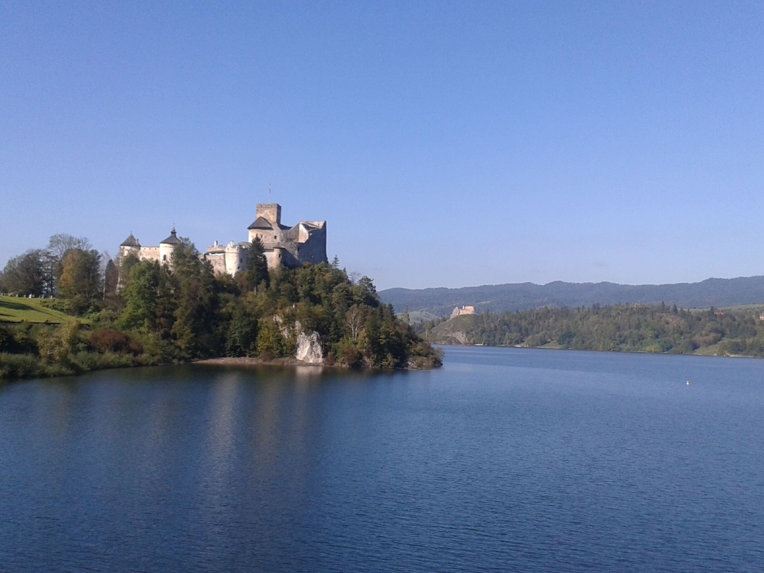 A castle on a hill overlooking a calm lake.