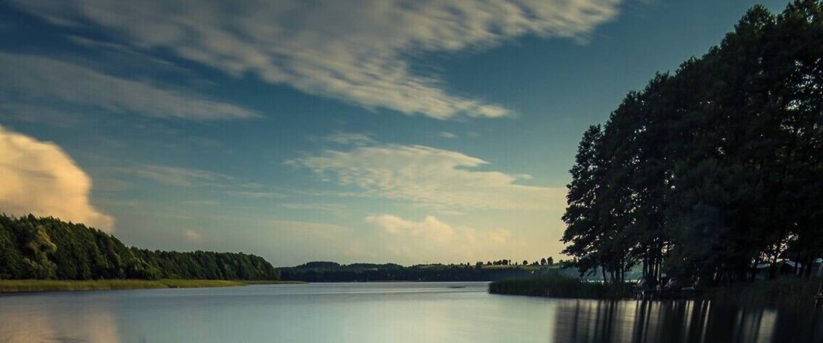 A wooden pier extending into calm water with a clear sky above.