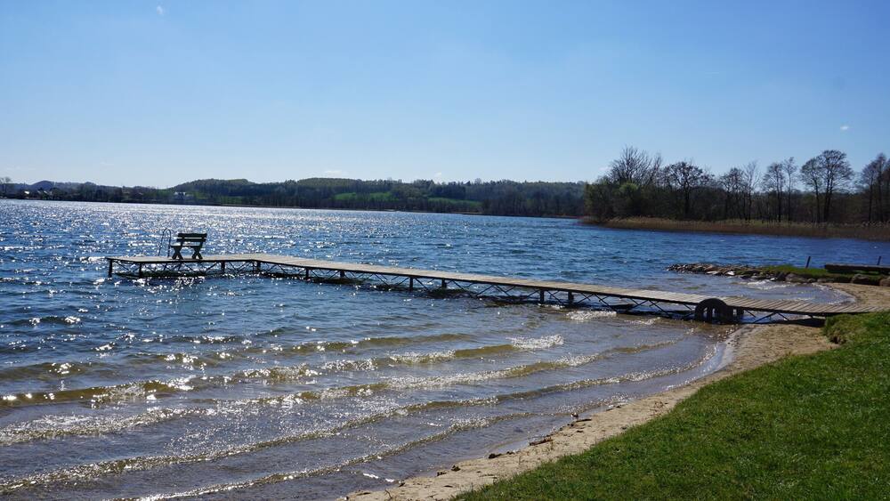A wooden pier extending into a lake with a bench at the end.