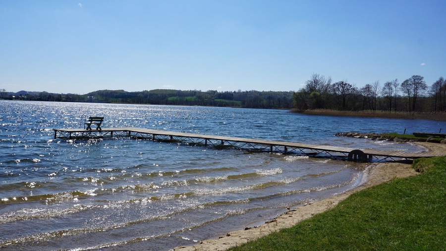 A wooden pier extending into a lake with a bench at the end.