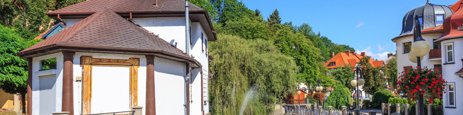 Polanica Zdroj - Bystrica Dusznicka flowing through the spa center along the promenade. On the hill visible tower of neo-baroque Church of the Assumption of the Blessed Virgin Mary built in 1912; Shut