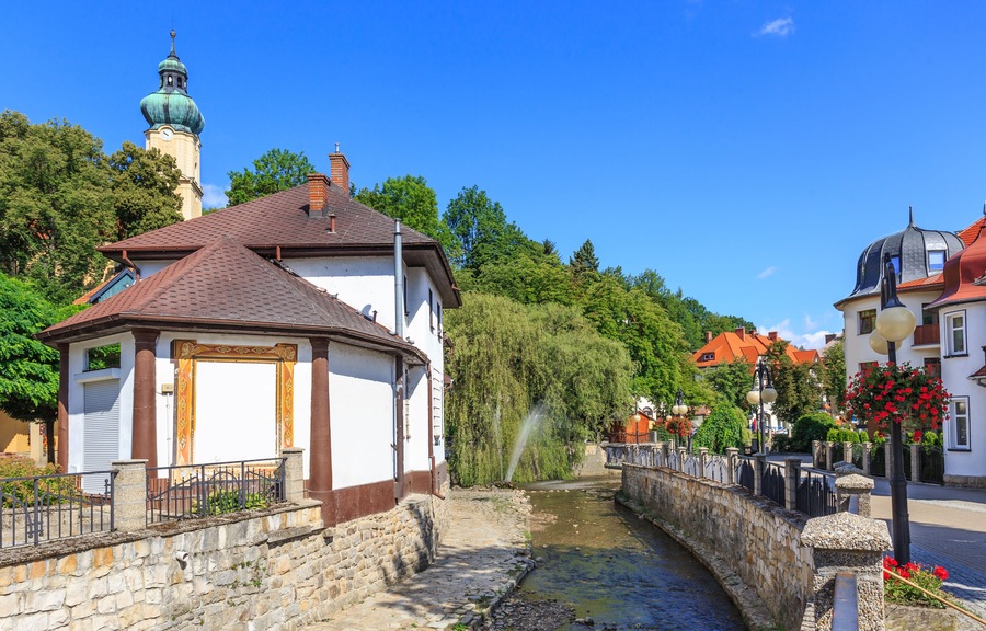 Polanica Zdroj - Bystrica Dusznicka flowing through the spa center along the promenade. On the hill visible tower of neo-baroque Church of the Assumption of the Blessed Virgin Mary built in 1912; Shut