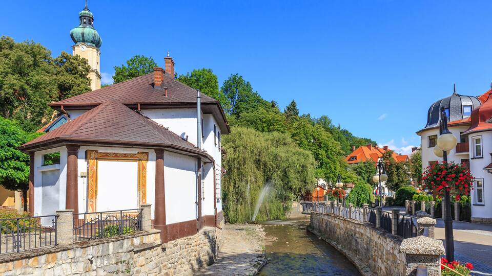 A stone bridge, a canal, and a church with a green dome.