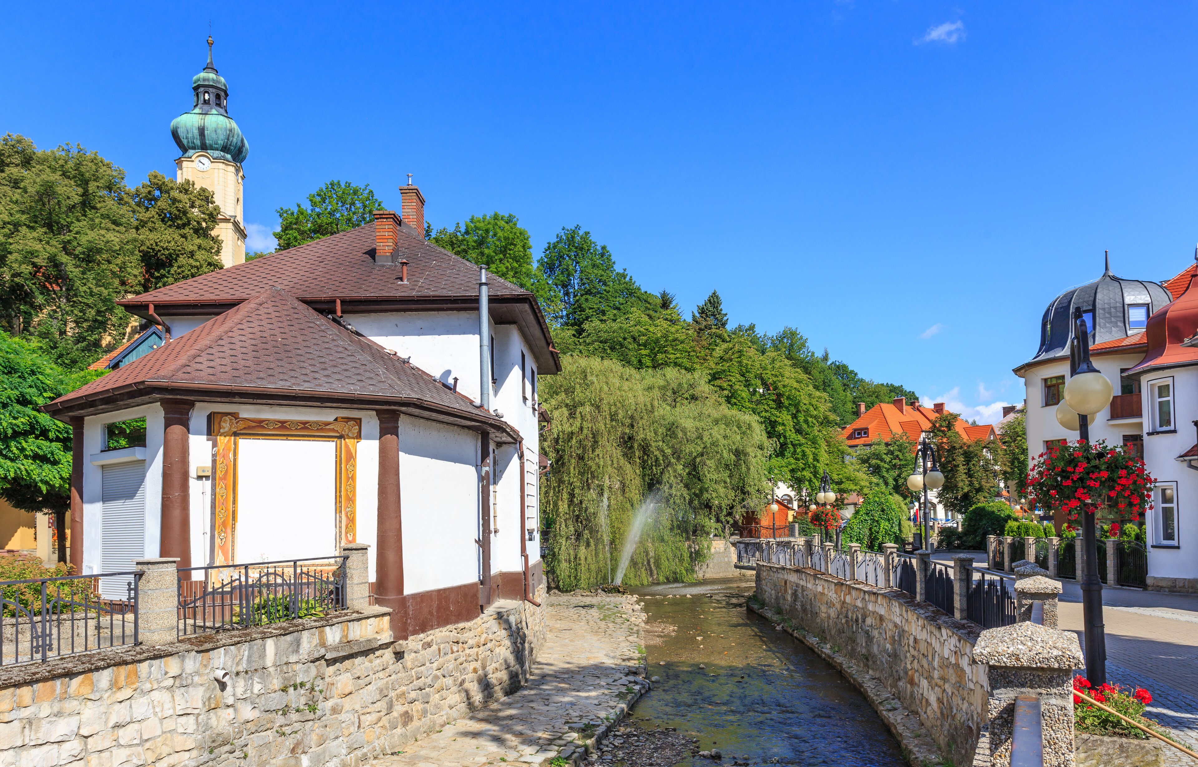 A stone bridge, a canal, and a church with a green dome.