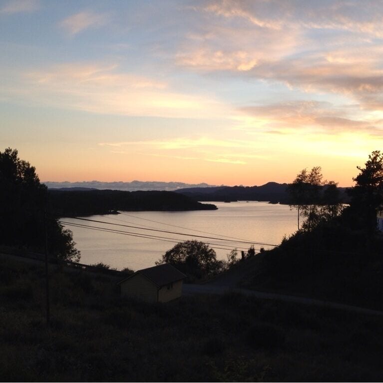 A sunset over a calm lake with hills in the background.
