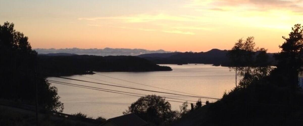 A sunset over a calm lake with hills in the background.