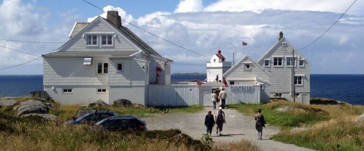 A coastal road with a white house and a lighthouse.