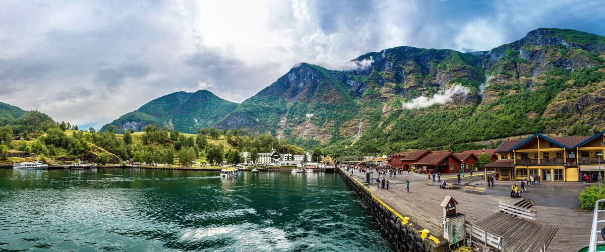 A lake with boats, a wooden pier, and buildings in the background.