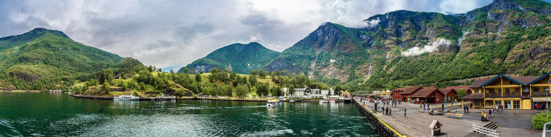 A lake with boats, a wooden pier, and buildings in the background.