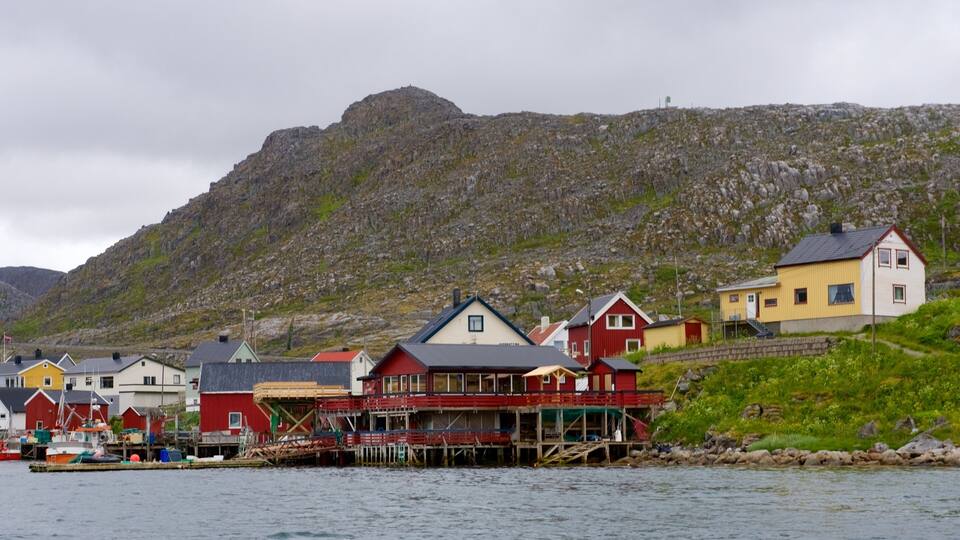 A coastal village with colorful houses and a rocky mountain in the background.