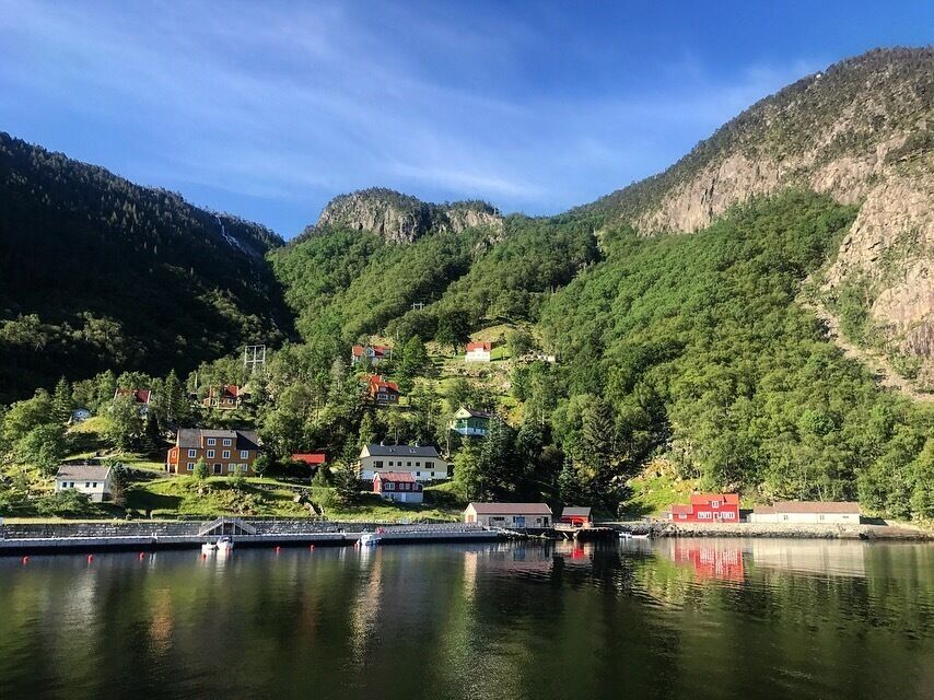 A lake with houses on the hillside and a bridge in the foreground.