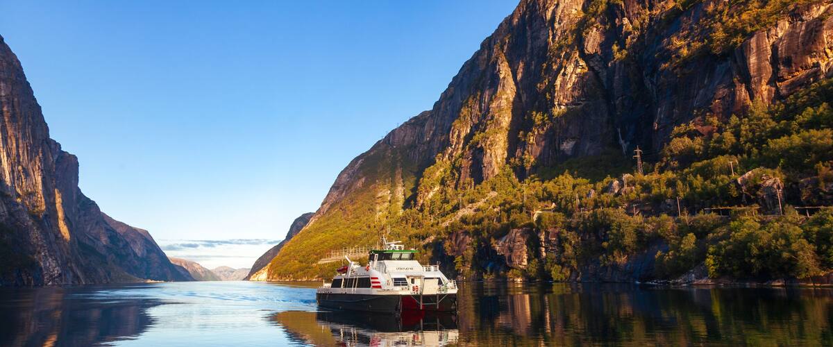 A riverboat on a calm river flanked by steep cliffs.