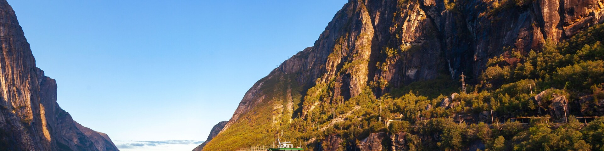 A riverboat on a calm river flanked by steep cliffs.