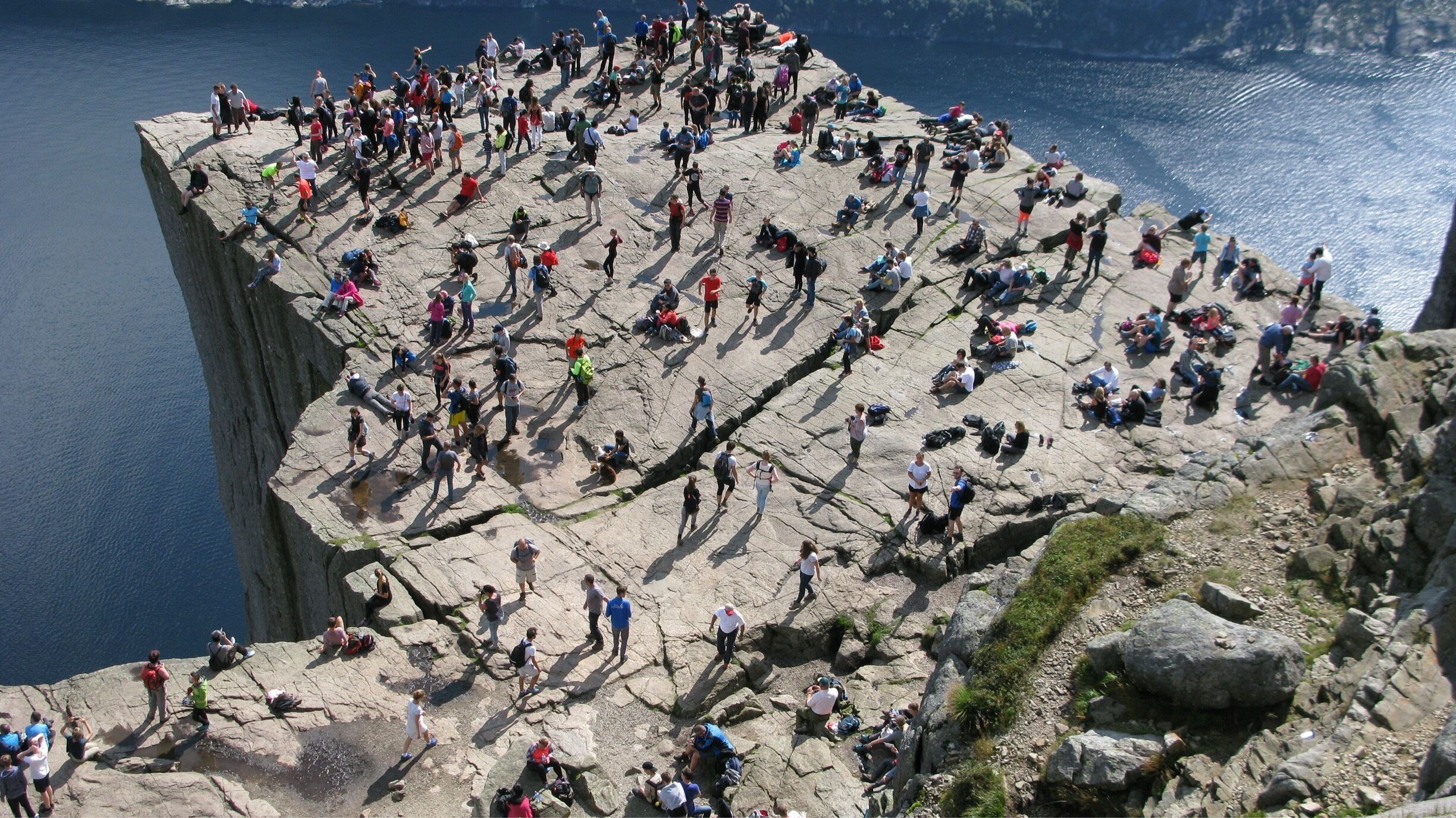 A crowded rocky cliff by a body of water.
