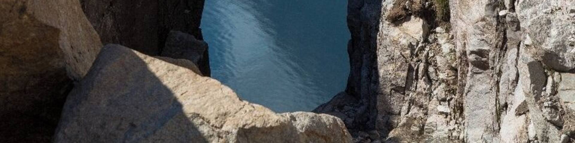 A rock formation with a natural arch over a body of water.