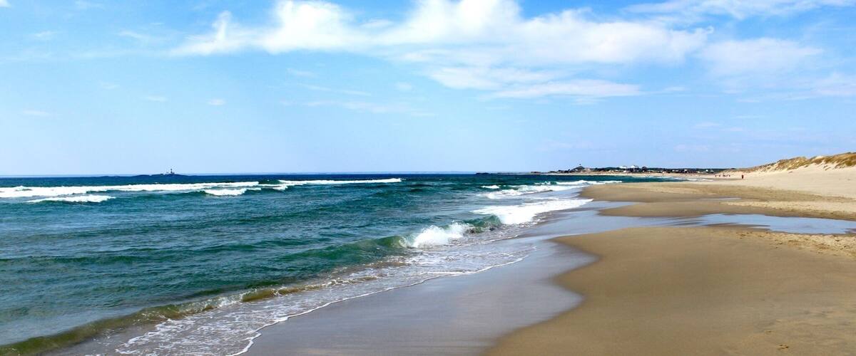 A sandy beach with gentle waves and a clear blue sky.