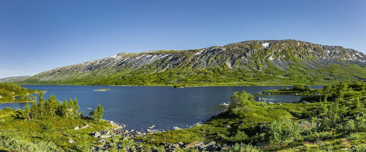 A mountainous landscape with a lake and surrounding greenery.