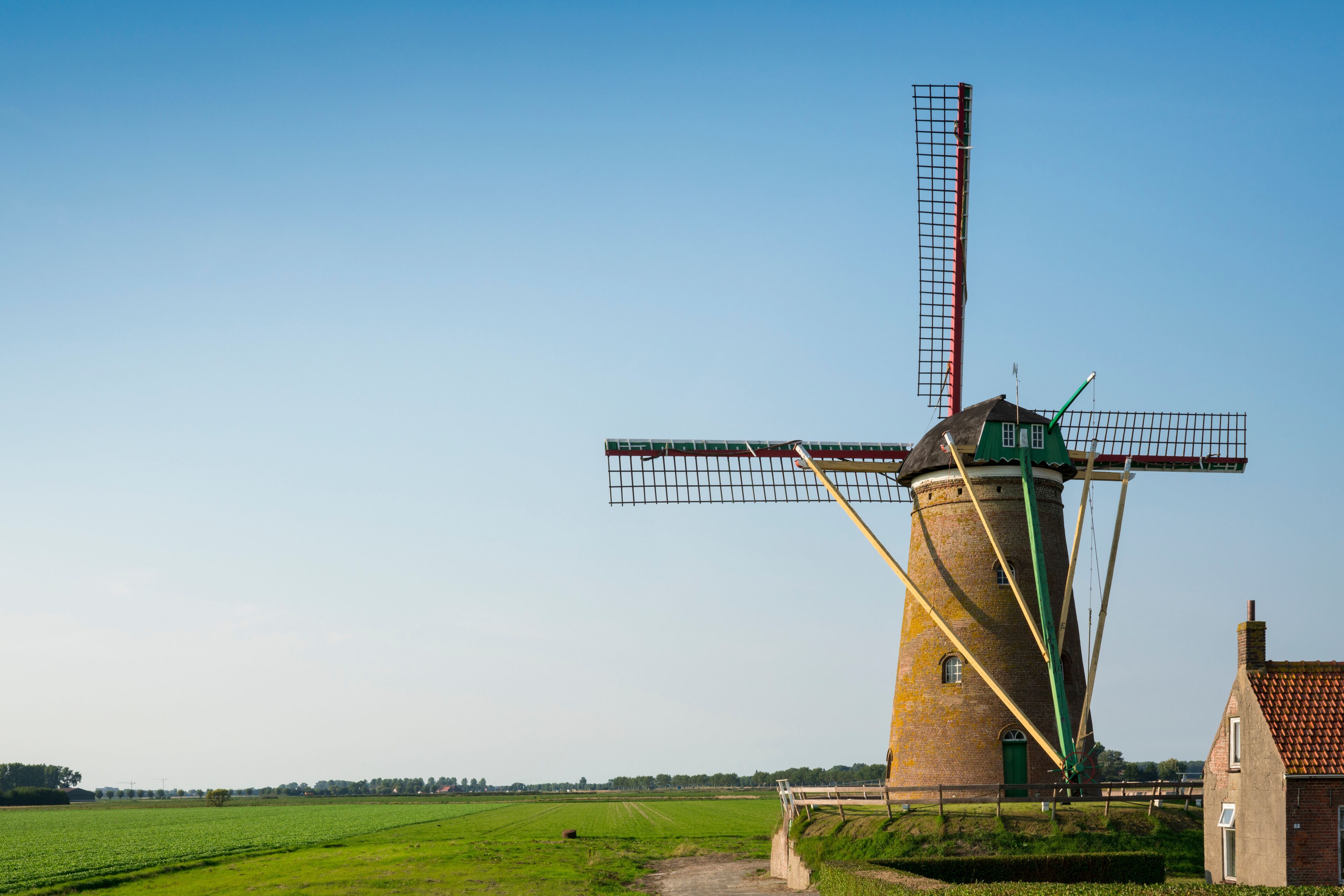 A traditional windmill with a green roof and a tall lattice structure.