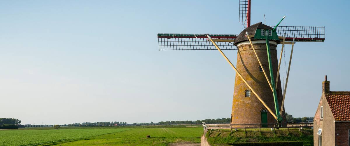 A traditional windmill with a green roof and a tall lattice structure.