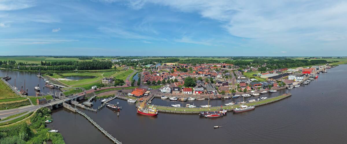 A riverside town with a bridge, boats, and surrounding greenery.
