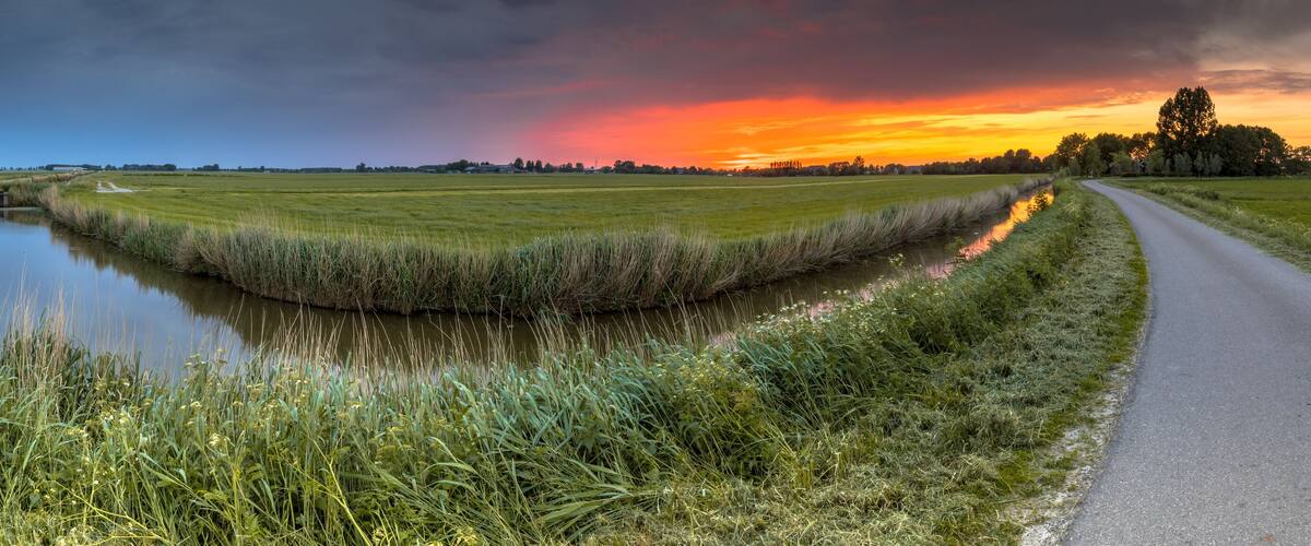 A rural landscape with a canal, a road, and fields.
